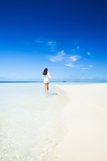 Frau läuft weg auf einem Strand in Malediven