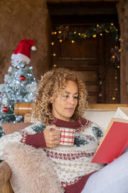 Frau las ein Buch mit Weihnachtsschmuck im Hintergrund