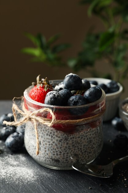 Frau legt Blaubeere in Glas mit Chia-Pudding