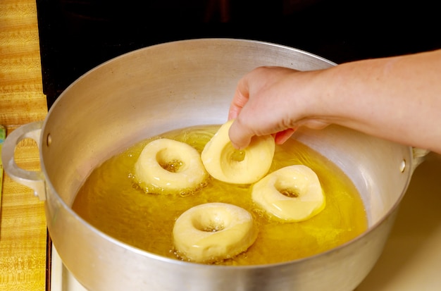 Frau legt rohe Donuts in heißes Öl