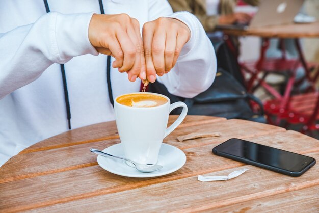 Frau legte Zucker in Tasse mit Latte