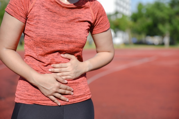 Foto frau leidet unter bauchschmerzen durch laufen oder training.