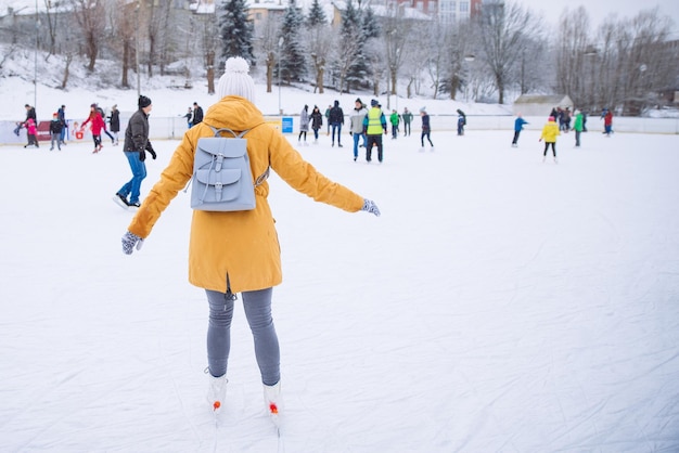 Frau lernt auf der Eisbahn der Stadt Skifahren