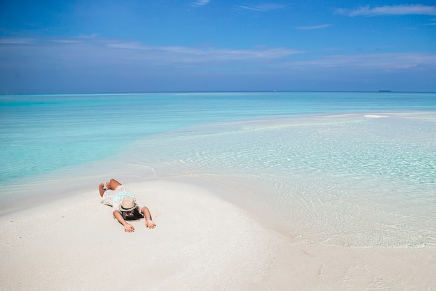 Frau liegt am Strand und genießt die Sommerferien mit Blick auf das Meer