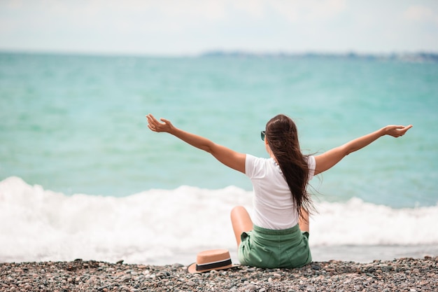 Frau liegt am Strand und genießt die Sommerferien mit Blick auf das Meer