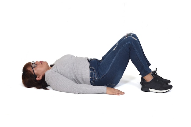 Frau liegt auf dem Boden mit hochgezogenen Beinen auf weißem Hintergrund