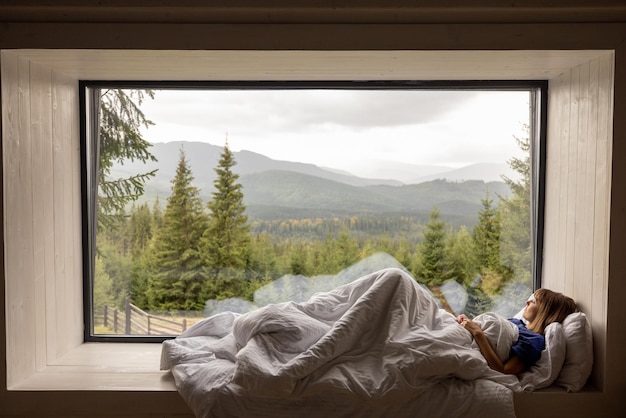 Frau liegt auf der Fensterbank mit toller Aussicht auf die Berge