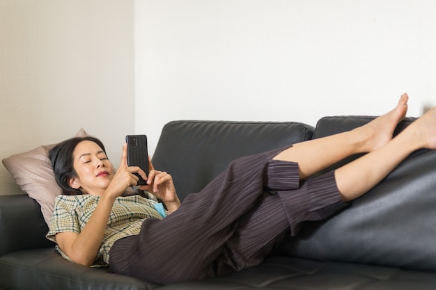 Frau liegt auf einer Couch mit Smartphone