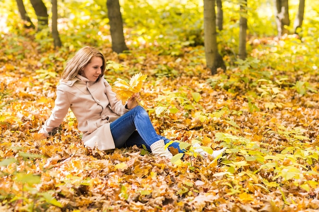 Frau liegt auf Herbstlaub, Outdoor-Porträt.