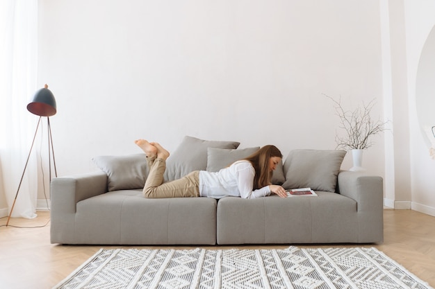 Frau liest auf der Couch zu Hause