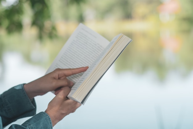 Frau liest Buch im schönen Park und Teich entspannen und friedlichen Umgebungshintergrund.