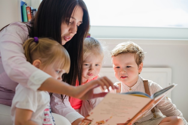 Frau liest Buch zu Kindern