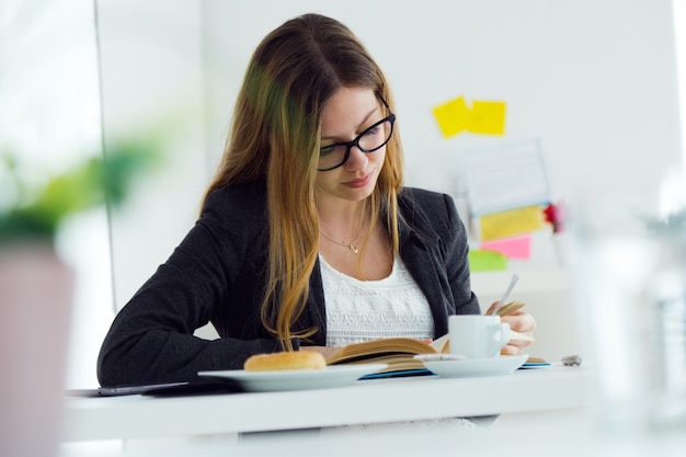 Frau liest ein Buch auf dem Frühstück