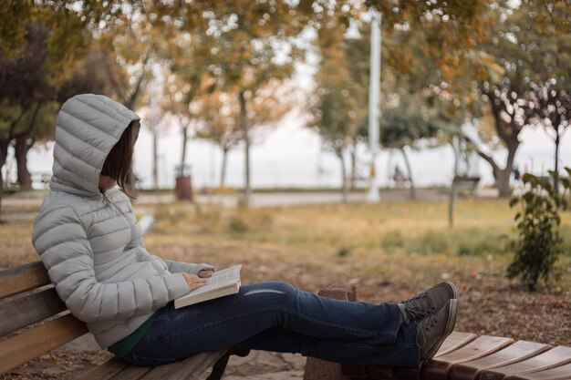 Foto frau liest ein buch auf einer bank im park
