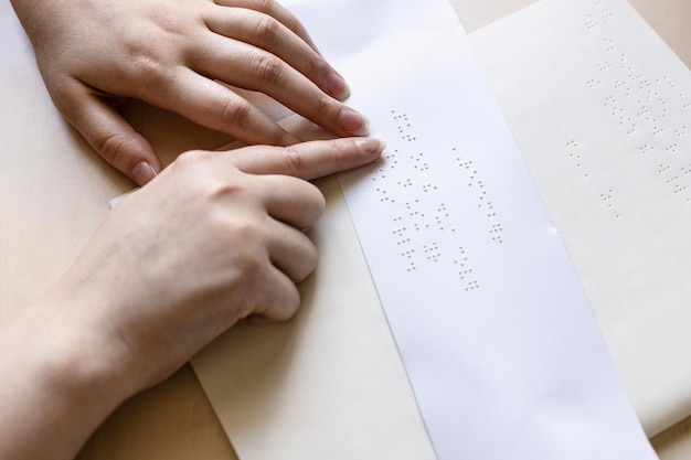 Frau liest Notiz in Blindenschrift auf einem Blatt Papier