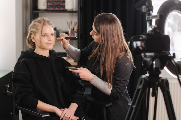 Frau machen Make-up für attraktive blonde Haare Frau im Studio. Video des Maskenbildners, der sich bewirbt