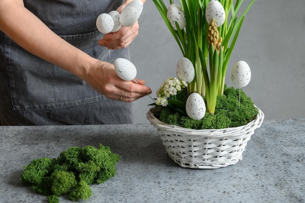 Frau machen osterblumenkomposition mit eiern dekorativem moos und häschen