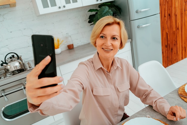 Frau macht beim Frühstück ein Selfie mit dem Smartphone