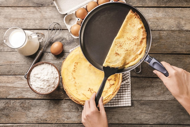 Frau macht dünne Pfannkuchen auf der Pfanne in der Küche