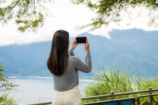 Frau macht ein Foto mit dem Handy auf dem Meer mit dem Berg