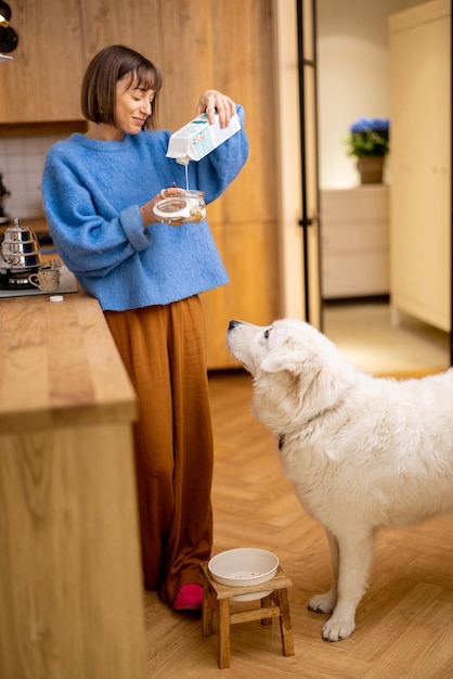 Frau macht ein Frühstück mit ihrem Hund in der Küche