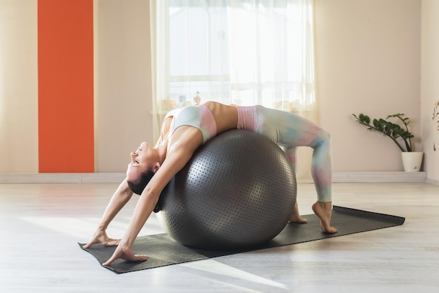 Frau macht eine Variation der Urdhva Dhanurasana-Übung mit Fitnessball-Brücke-Pose