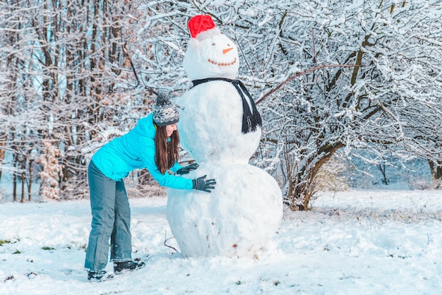 Frau macht einen Schneemann im frostigen Wintertagkonzept