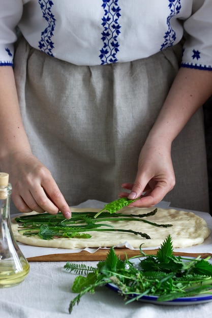 Frau macht Focaccia aus Hefeteig mit verschiedenen Kräutern. Rustikaler Stil.