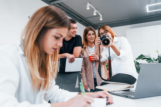 Frau macht Foto per Kamera Gruppe von Geschäftsleuten in formeller Kleidung drinnen im Büro