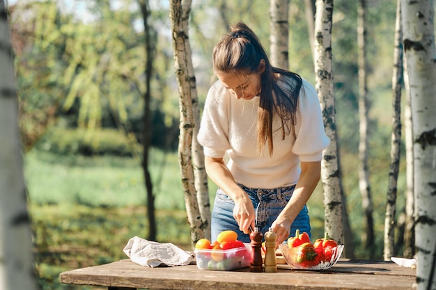 Frau macht Gemüsesalat im Freien beim Picknick an sonnigen Tagen