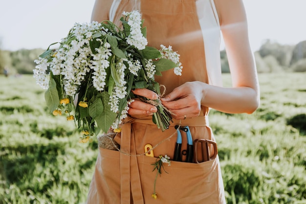 Frau macht Kranz aus Blumen Löwenzahn auf blühendem Feld Sommerlebensstil