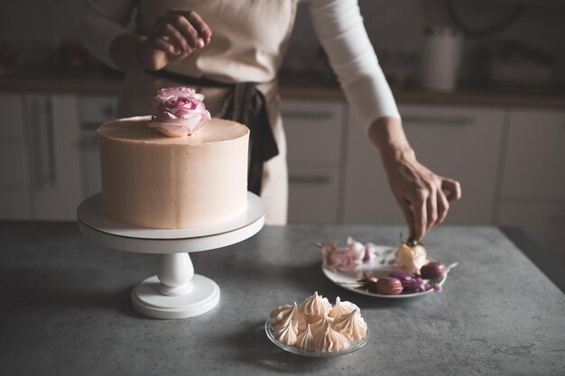 Frau macht Kuchen mit Blumenrosen dekorieren