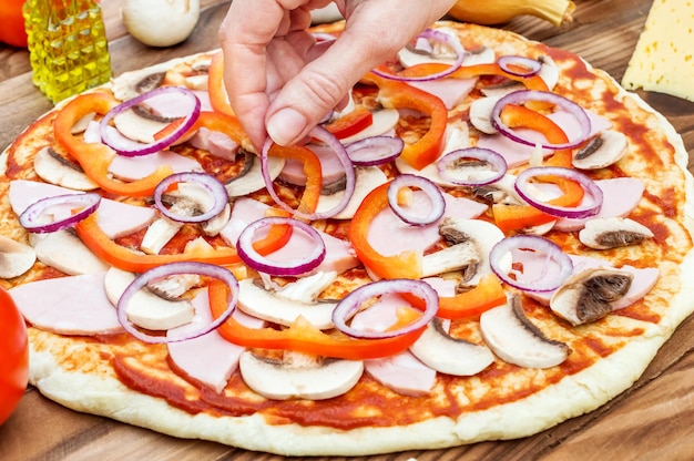 Frau macht Pizza auf Holztisch Essen zubereiten hautnah