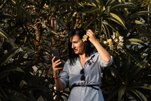 Frau macht Selfie im Garten mit Blumen