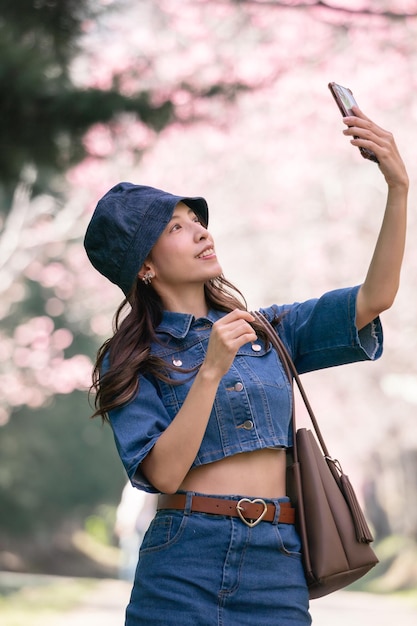 Frau macht Selfie mit Kirschblüten oder Sakura-Blüten, die im Park blühen