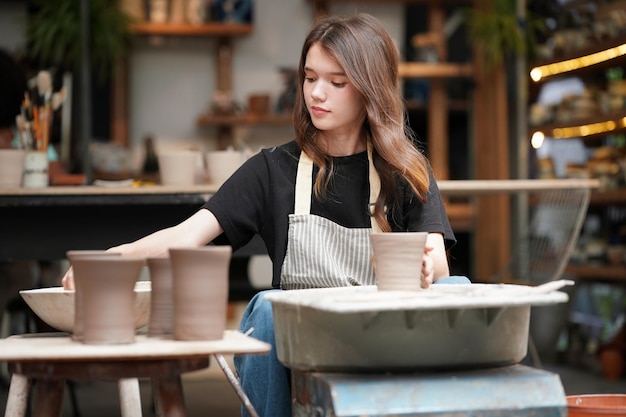 Foto frau macht töpferei in der werkstatt nassen ton auf der töpferscheibe formen