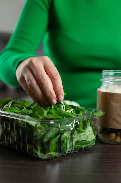 Frau macht veganen Salat in einem Glas mit Kichererbsen und kocht gesundes Essen