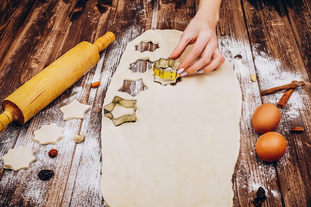 Frau macht Weihnachtsgebäck auf dem Teig auf Holztisch