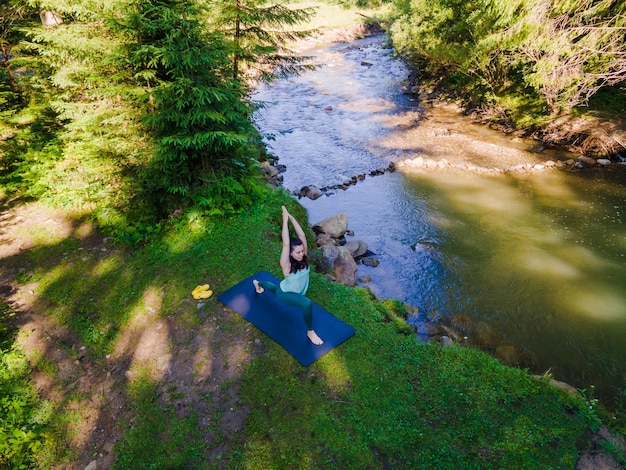 Foto frau macht yoga am flussstrand