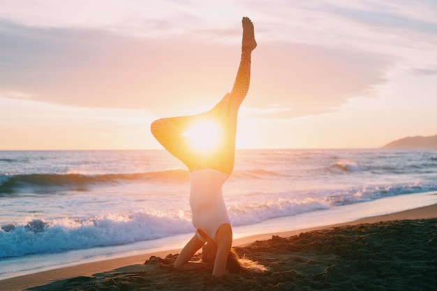 Foto frau macht yoga am strand während des sonnenuntergangs