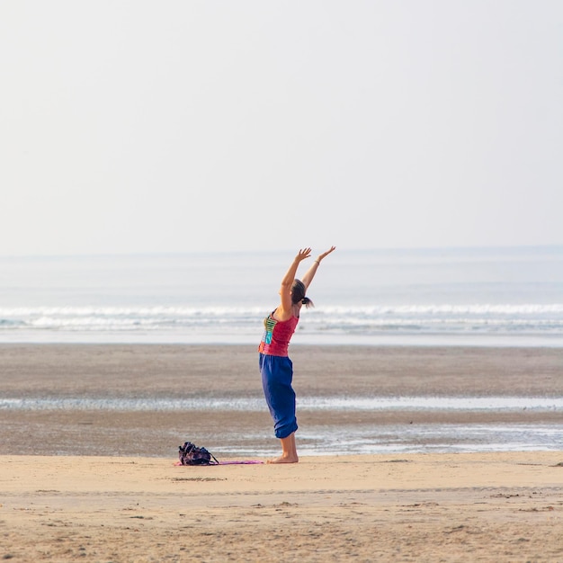 Frau macht Yoga am Strand