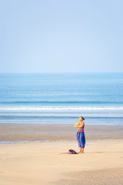 Frau macht Yoga am Strand