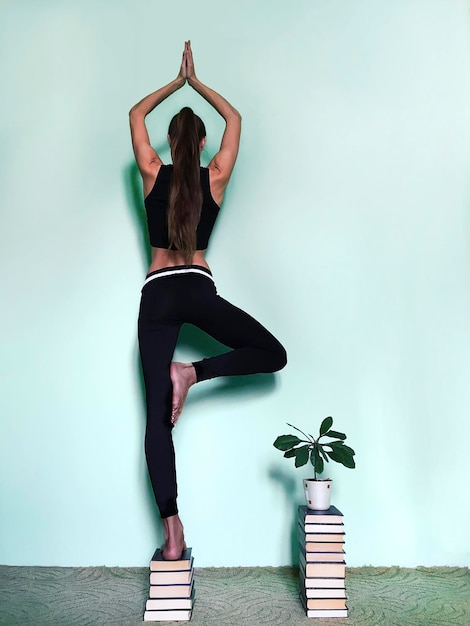 Frau macht Yoga auf Büchern gegen die Wand zu Hause