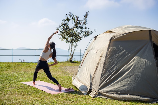 Frau macht Yoga auf dem Campingplatz