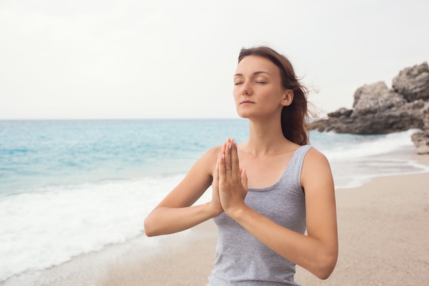 Frau macht Yoga auf dem Meereshintergrund