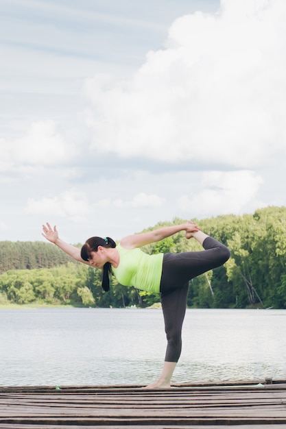 Frau macht Yoga auf der Brücke im Sommer