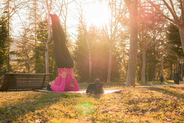 Frau macht Yoga-Übungen in einem Park bei Sonnenuntergang