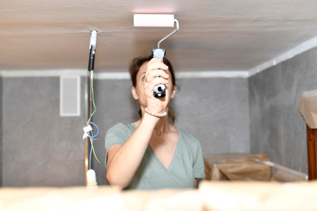 Foto frau malt die decke zu hause und renoviert das gemälde im bau oder in der reform