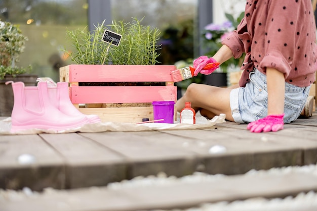 Frau malt Holzkiste in rosa Farbe DIY-Konzept