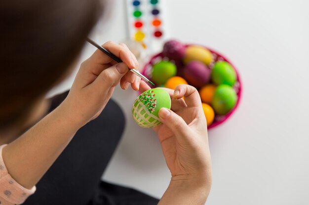 Frau malt Ostereier bunte Bürste Handwerk weißer Hintergrund Traditionelle Feiertagsdekoration